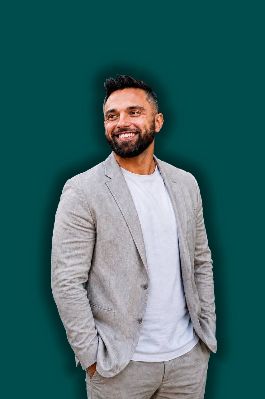 Dr. Ian Quinn in a light gray linen suit, smiling against a dark teal background